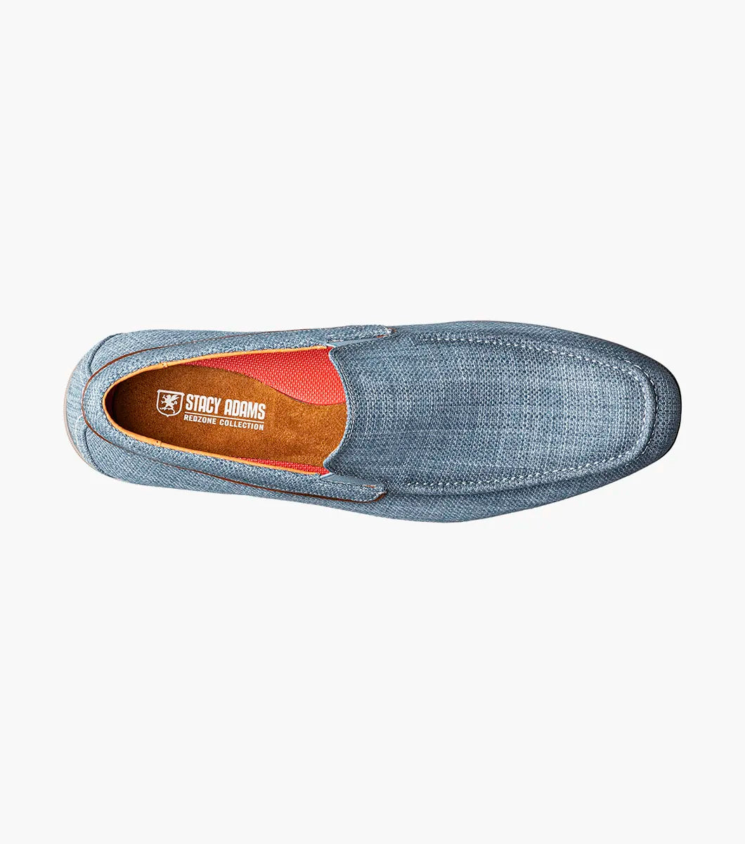 The Stacy Adams Ridgely Moc Toe Slip On in navy features a textured fabric upper, breathable leather lining, brown trim, and a low stacked wooden heel, shown against a white background.