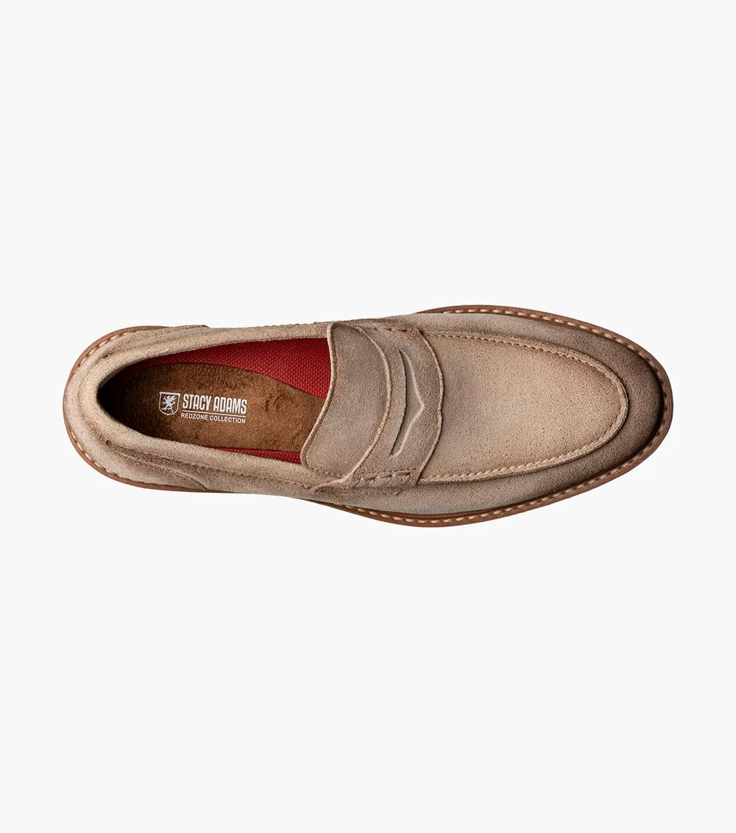 The STACY ADAMS Hopkins Moc Toe Penny Slip On in Sand (25708-269) is a light brown suede loafer with a white and tan rubber sole and red interior lining, shown on a white background.