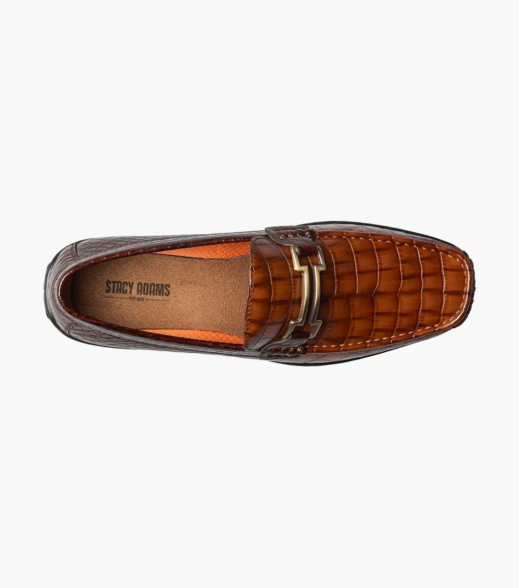 The STACY ADAMS Embrey Moc Toe Bit Slip On in Cognac (25703-221) features brown crocodile print leather, a metallic buckle, a cushioned footbed for comfort, slip-on design, and is showcased against a plain white background.