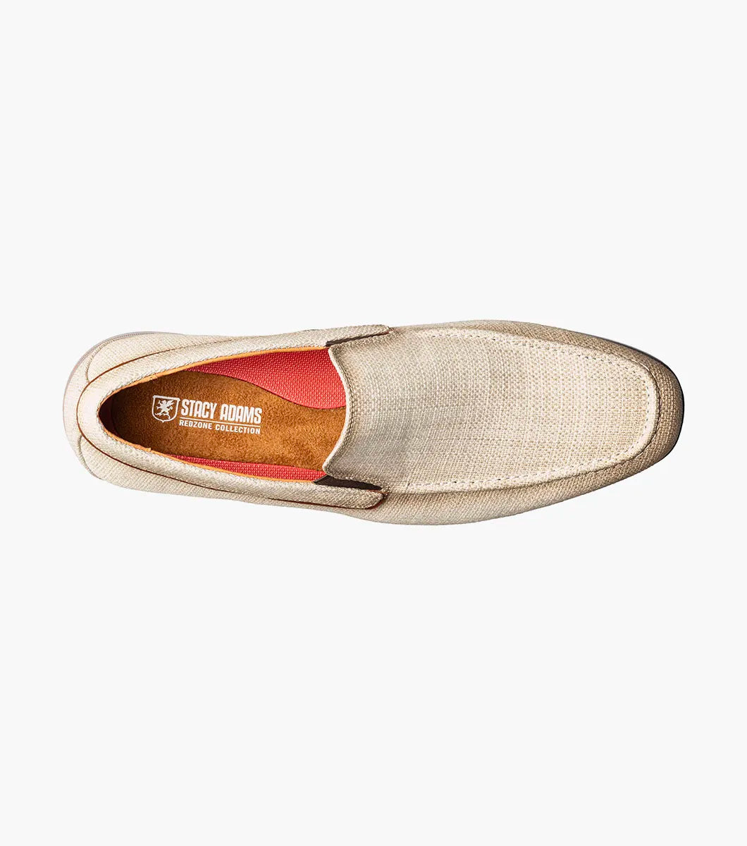 The Stacy Adams Ridgely Moc Toe Slip On (Natural) features a textured fabric upper, brown trim, anatomical arch support, and a low wooden heel for comfort, shown here on a white background.