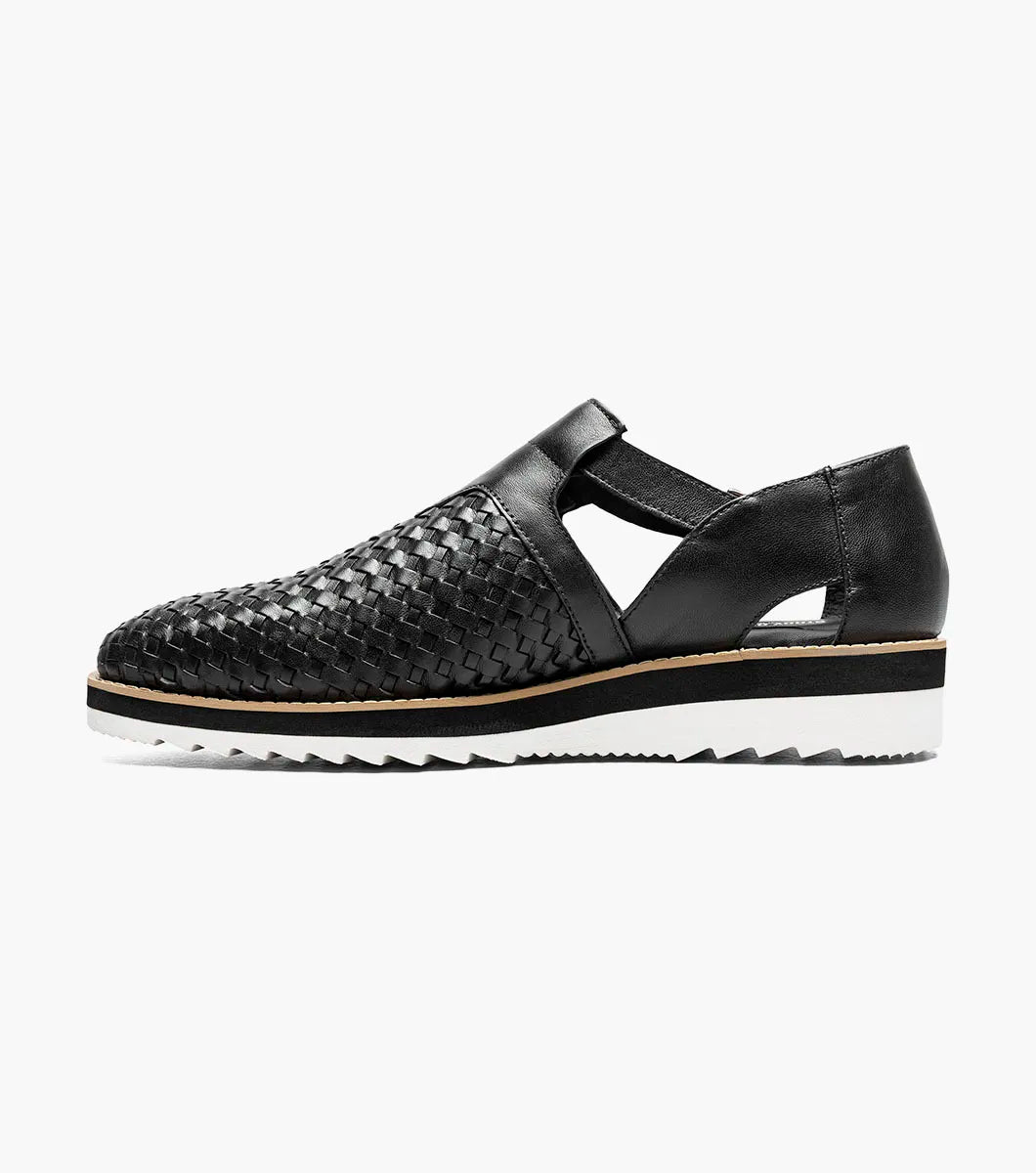 The Stacy Adams Alvarado Woven City Sandal features a black woven leather upper, buckle strap, closed toe, memory foam insole, and a white ridged sole with tan accent.