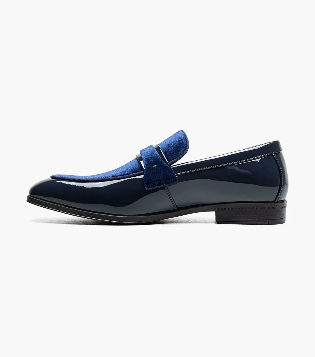 The Stacy Adams Spratley Moc Toe Saddle Slip On (25686-410) features shiny navy blue leather, a matching velour upper, cushioned insole, and low black heel. Displayed solo on a white background.