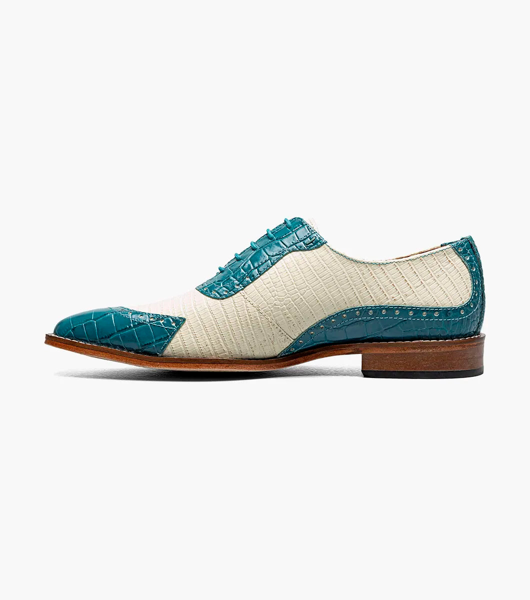 The STACY ADAMS Tarango Modified Cap Toe Oxford (25770-448) is a men's formal shoe in navy with teal, showcasing crocodile print leather and a laceless design, pictured on a plain white background.