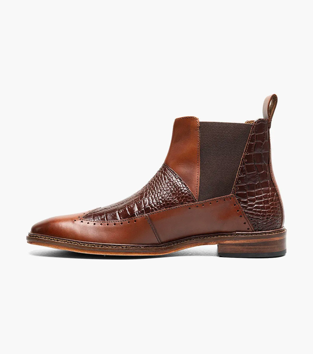 The Stacy Adams Garza Wingtip Chelsea Boot in Cognac features crocodile texture detail, elastic side panel, heel pull tab, cushioned footbed for comfort, and a low wooden sole.