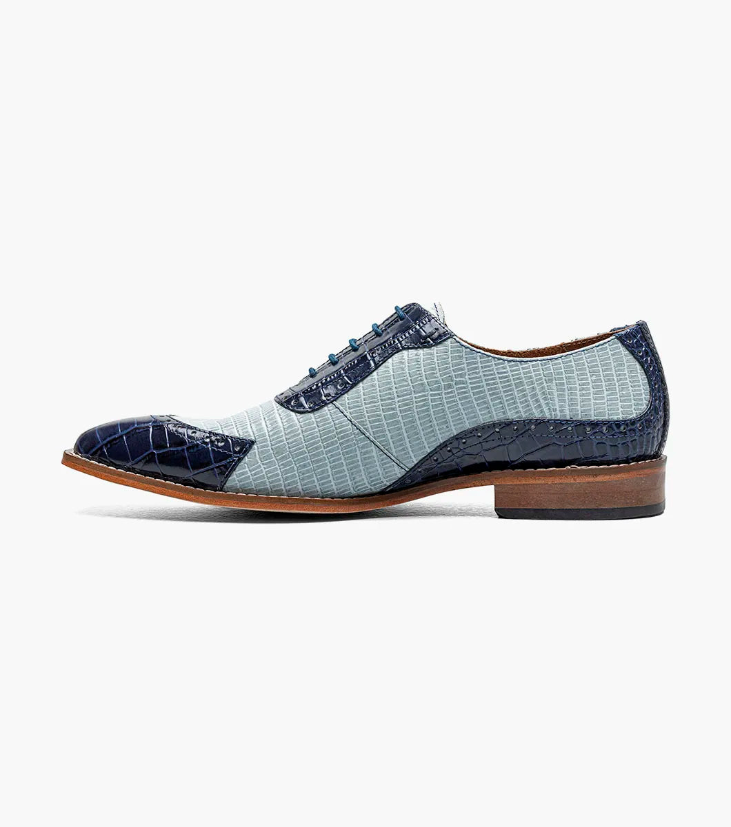 The Stacy Adams Tarango Modified Cap Toe Oxford in Dark Blue Multi features pointed toes, gray and blue crocodile print leather, and a low wooden heel—ideal for formal shoe enthusiasts.