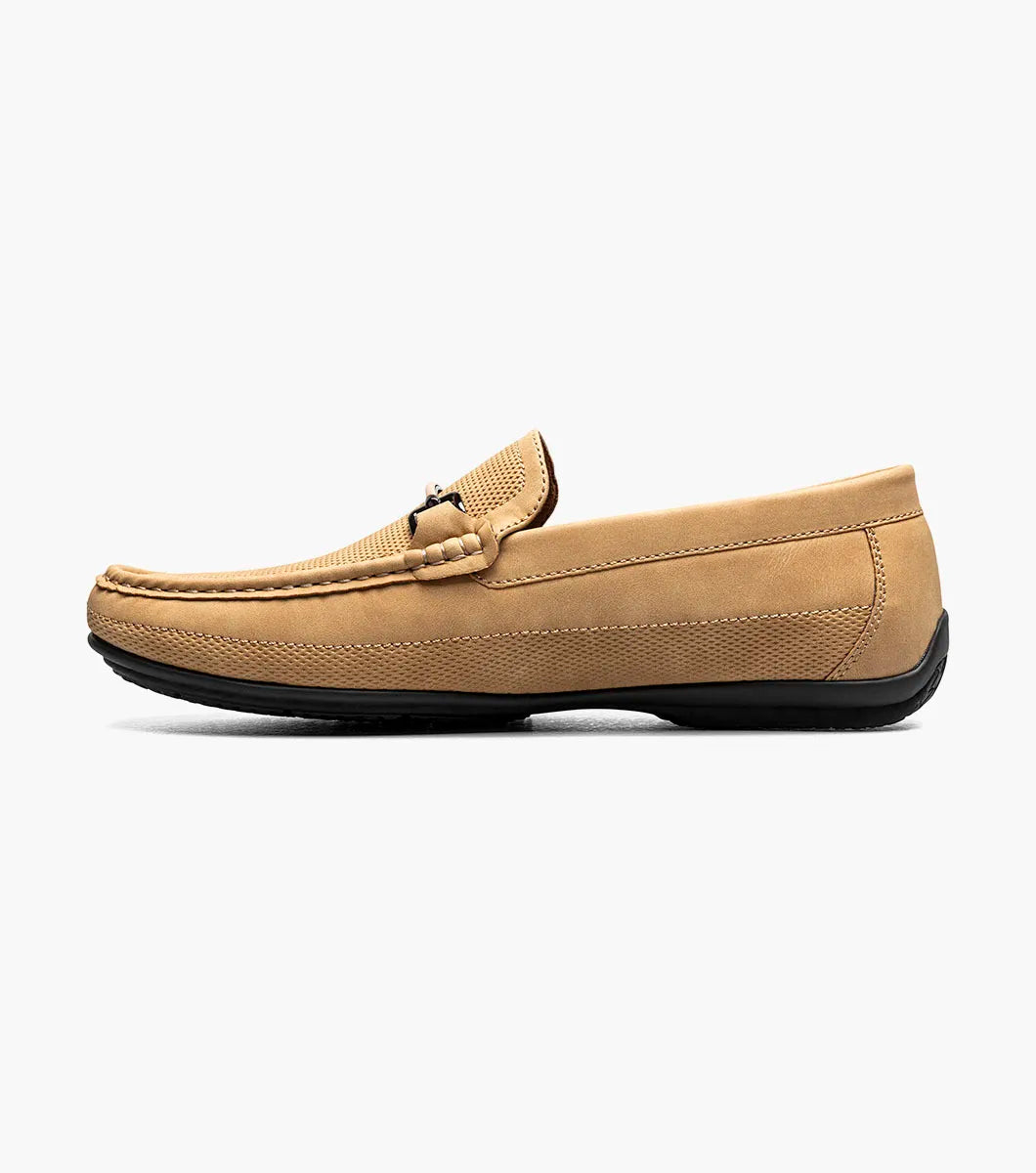 The Stacy Adams Colton Moc Toe Bit Slip On in khaki features a stitched moc toe, metal bit detail, black rubber sole, multicolored striped lining, and cushioned footbed for all-day comfort.