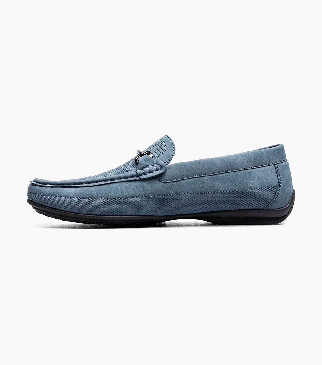 The STACY ADAMS Colton Moc Toe Bit Slip On (Navy, 25760-410) features a cushioned footbed, metal bit detail, moc toe stitching, and a flat black sole, shown on a white background.