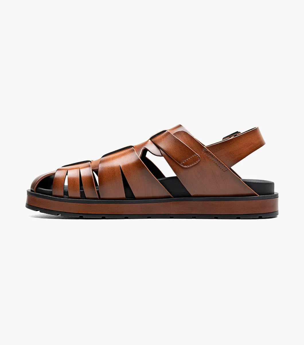 The STACY ADAMS Largo Slingback Buckle Sandal in cognac features a closed toe, woven leather upper, adjustable side buckle, and cushioned black sole—perfect men’s summer footwear. Shown here in style 25773-221 on a white background.