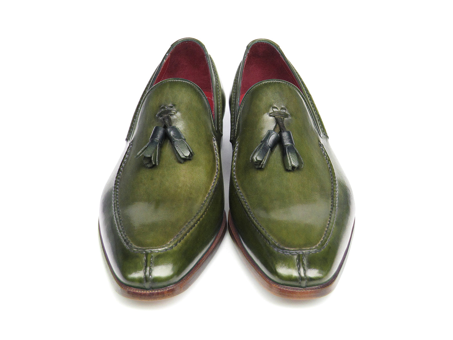 The Paul Parkman Tassel Loafer Green Hand Painted Leather - 083-GREEN features a pair of green hand-painted leather loafers with tassels and brown wooden soles; one shoe is upright, the other displays its sole.