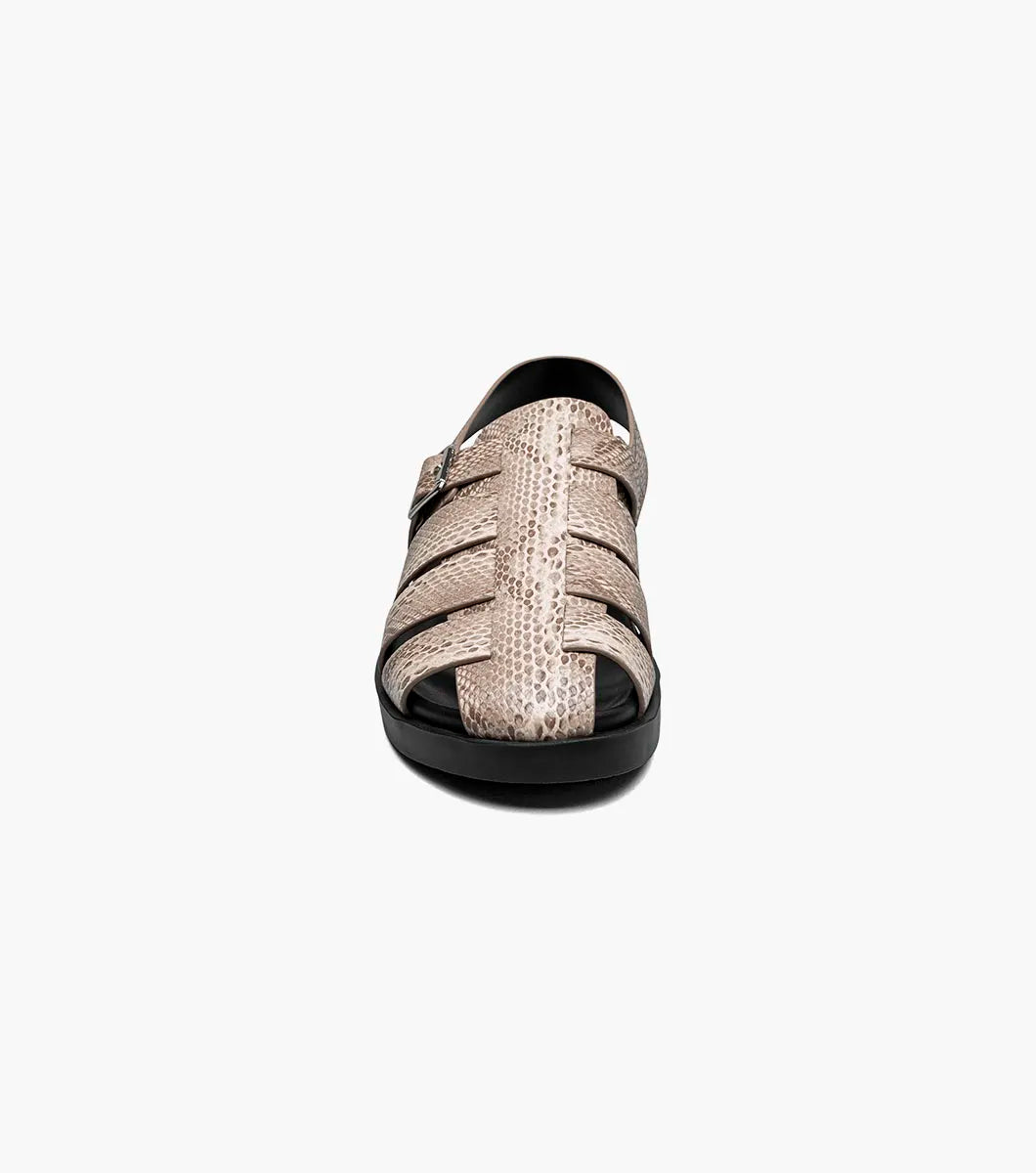 The Stacy Adams Montego Slingback Buckle Sandal (Sand, 25659-269) features a tan snakeskin pattern, closed toe, cutout sides, adjustable buckle strap, black sole, and cushioned EVA midsole on a white background.