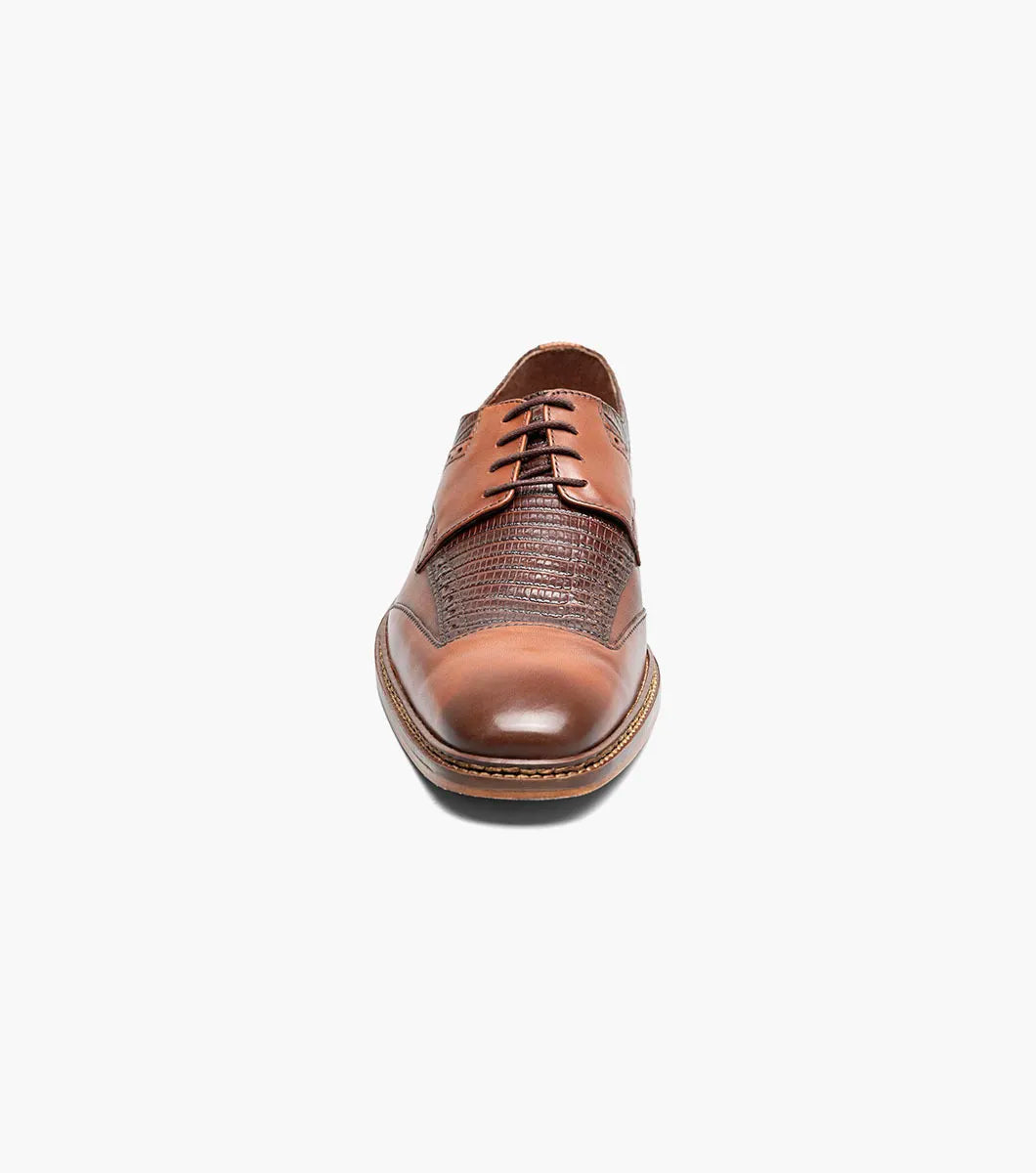The Stacy Adams Gambetta Modified Cap Toe Oxford in cognac features textured detailing, lace-up closure, and a low heel, displayed on a white background.