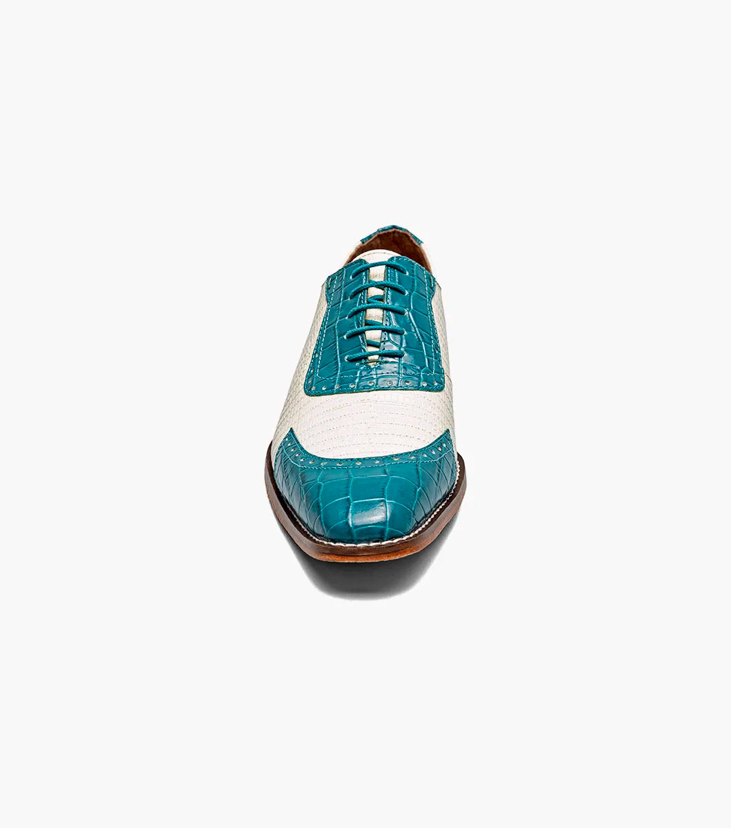 The STACY ADAMS Tarango Modified Cap Toe Oxford (25770-448) is a men's formal shoe in navy with teal, showcasing crocodile print leather and a laceless design, pictured on a plain white background.