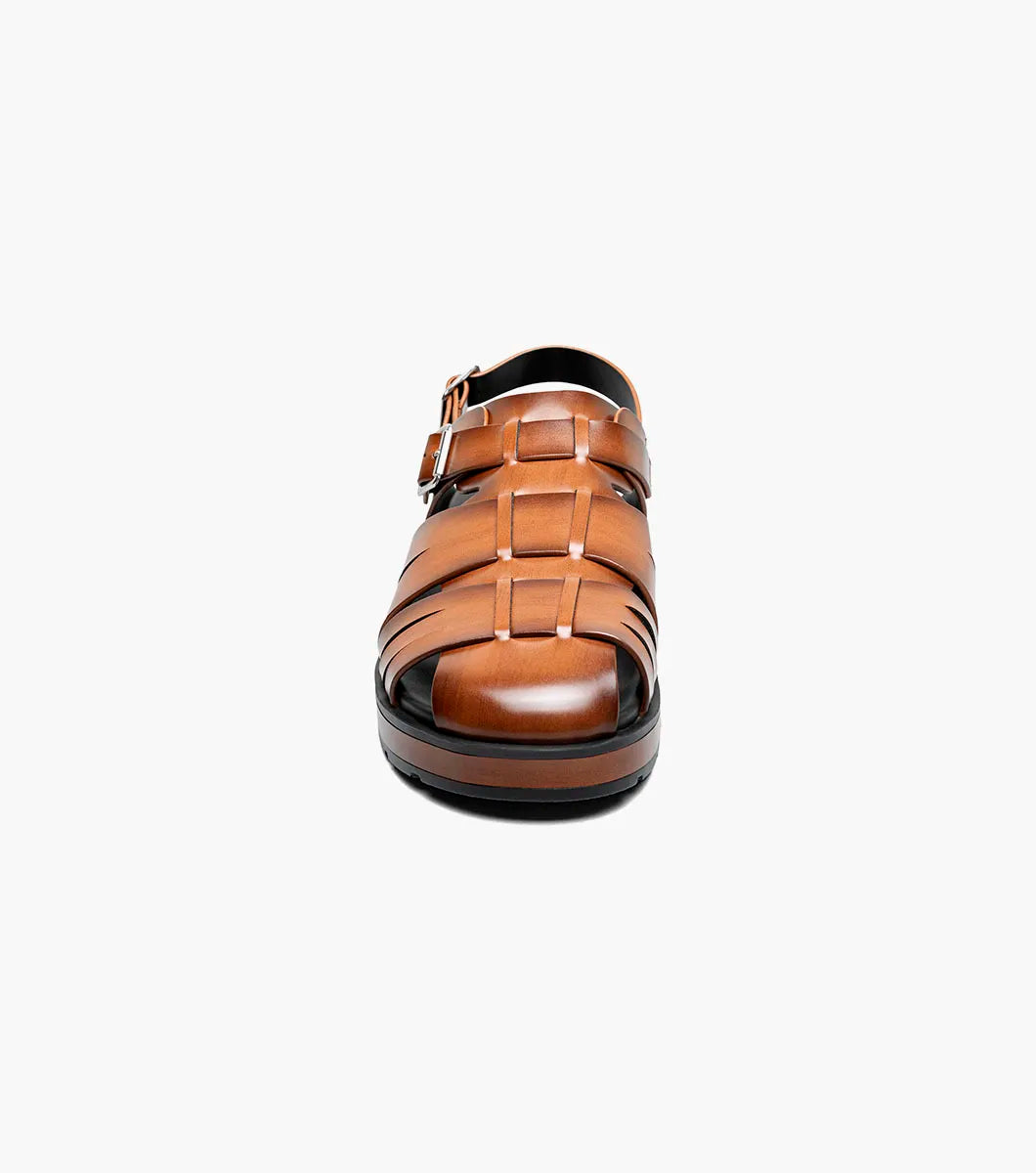 The STACY ADAMS Largo Slingback Buckle Sandal in cognac features a closed toe, woven leather upper, adjustable side buckle, and cushioned black sole—perfect men’s summer footwear. Shown here in style 25773-221 on a white background.