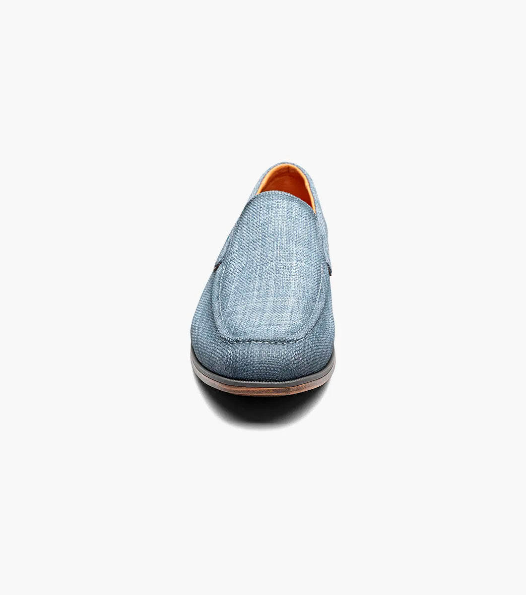 The Stacy Adams Ridgely Moc Toe Slip On in navy features a textured fabric upper, breathable leather lining, brown trim, and a low stacked wooden heel, shown against a white background.