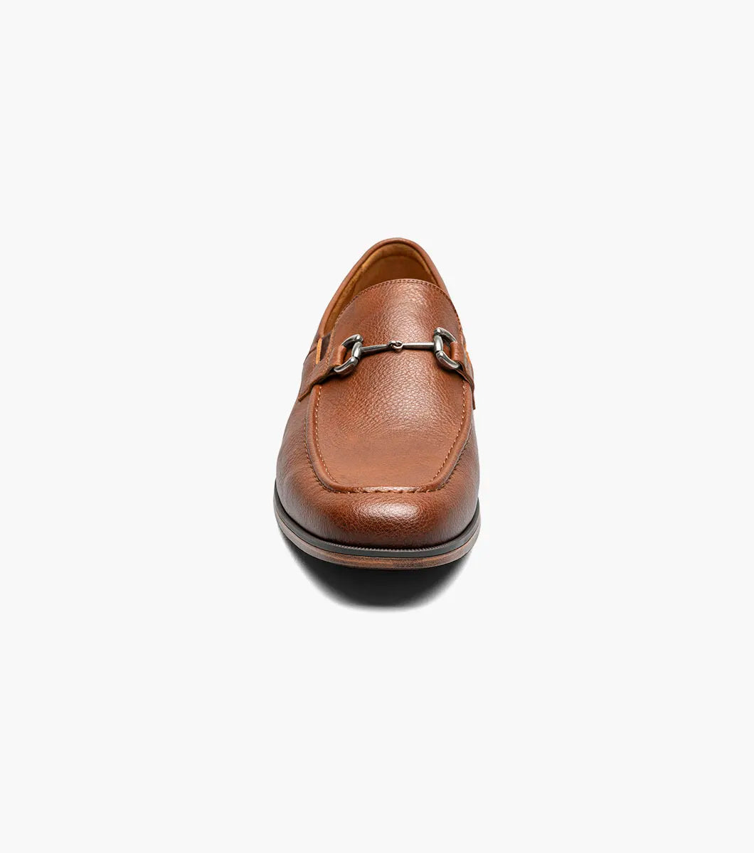 The STACY ADAMS Richmont Moc Toe Bit Slip On in Cognac Tumbled (21567-222) is a brown leather loafer with a metal bit, moc toe slip-on design, low wooden heel, and detailed toe stitching, shown on a white background.