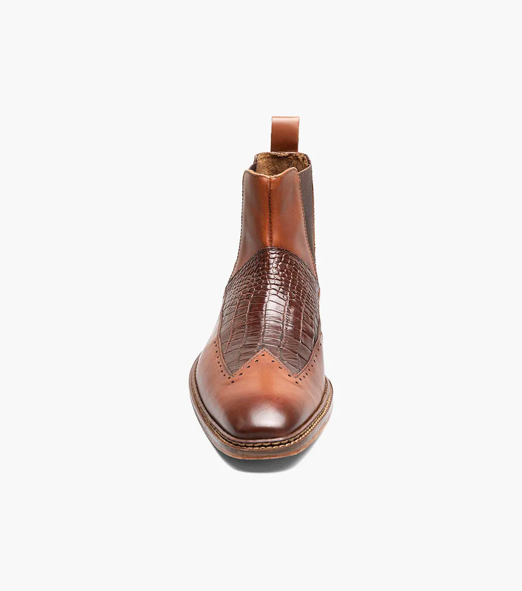 The Stacy Adams Garza Wingtip Chelsea Boot in Cognac features crocodile texture detail, elastic side panel, heel pull tab, cushioned footbed for comfort, and a low wooden sole.