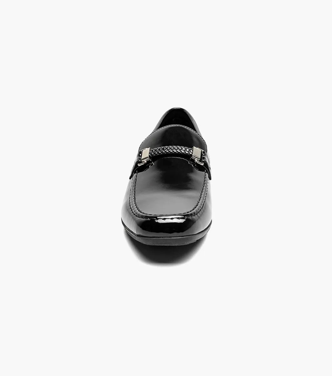 The STACY ADAMS Sheridan Moc Toe Bit Slip On (Black Patent, 25761-004) is shown: a single low-heeled loafer with black patent leather, braided strap detail, and classic styling on a plain white background.