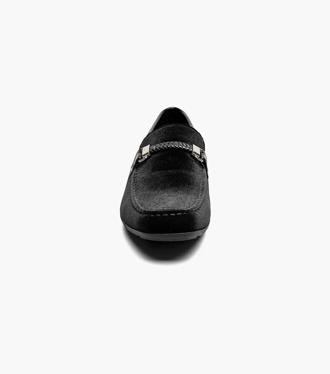 The Stacy Adams Sheridan Moc Toe Bit Slip On (black, 25761-001) is a sleek black suede dress shoe with braided detail and metal accent, low heel, and satin-lined interior for comfort.