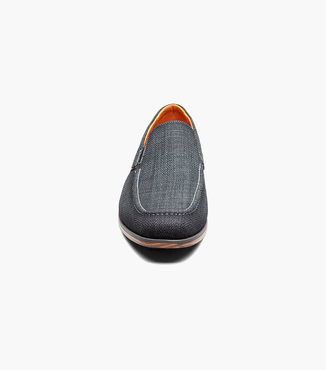 The Stacy Adams Ridgely Moc Toe Slip On in charcoal features visible stitching, a low wooden heel, comfy footbed, and tan lining. Shown against a white background, this casual loafer is perfect for everyday wear.