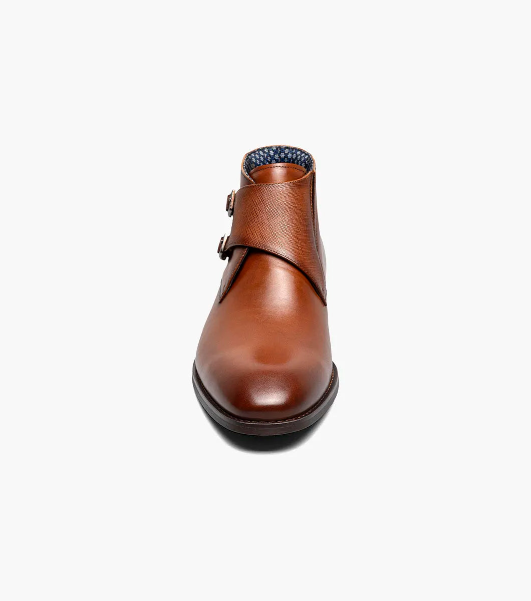 The STACY ADAMS Kaius Plain Toe Double Monk Strap Boot in Cognac (25733-221) features hand-burnished leather, a textured side panel, low stacked heel, and anatomical arch support, shown on a white background.