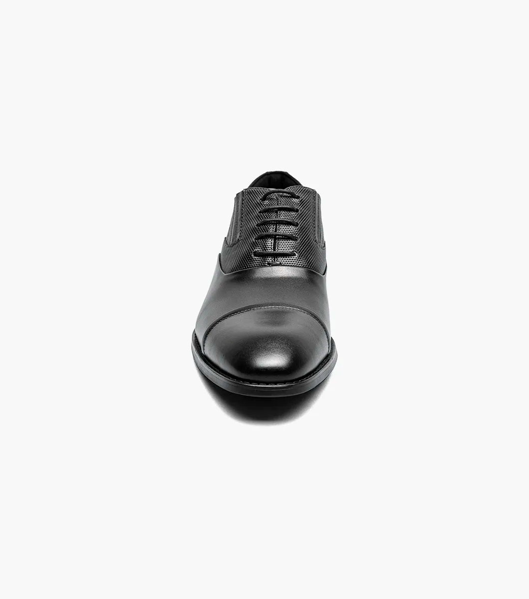 The STACY ADAMS Lucas Cap Toe Oxford (25766-001) is a black leather men's dress shoe with textured side panels, black laces, and a supportive RedZone footbed, shown on a plain white background.