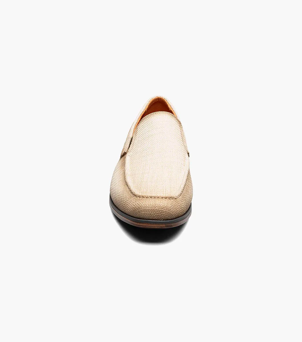 The Stacy Adams Ridgely Moc Toe Slip On (Natural) features a textured fabric upper, brown trim, anatomical arch support, and a low wooden heel for comfort, shown here on a white background.