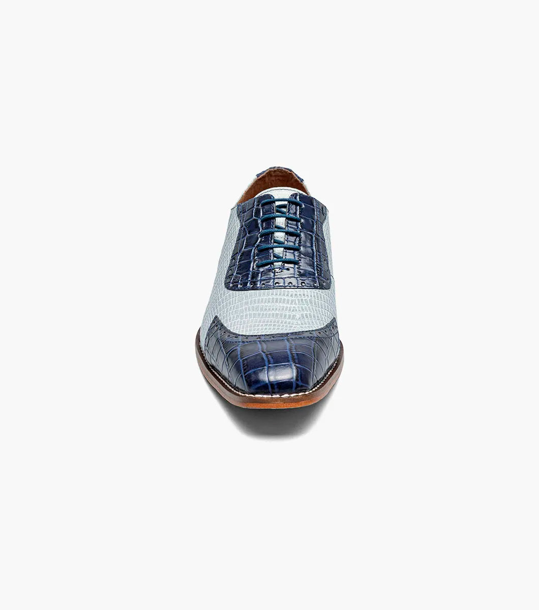 The Stacy Adams Tarango Modified Cap Toe Oxford in Dark Blue Multi features pointed toes, gray and blue crocodile print leather, and a low wooden heel—ideal for formal shoe enthusiasts.