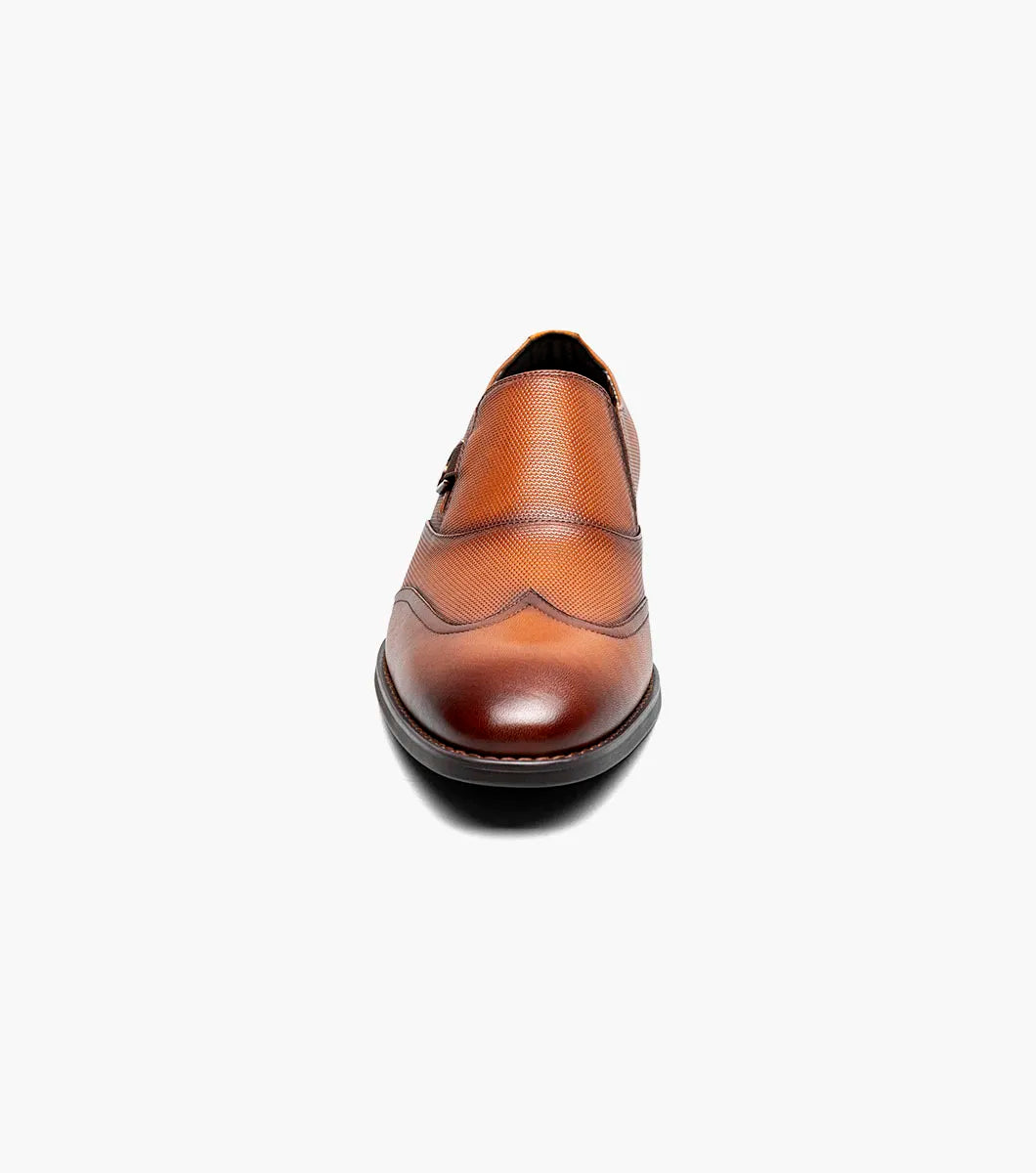 The Stacy Adams Lockwood Wingtip Ornament Slip On in Cognac features classic leather style with a textured upper, single side buckle, and low stacked heel—perfect for men seeking timeless dress shoes.