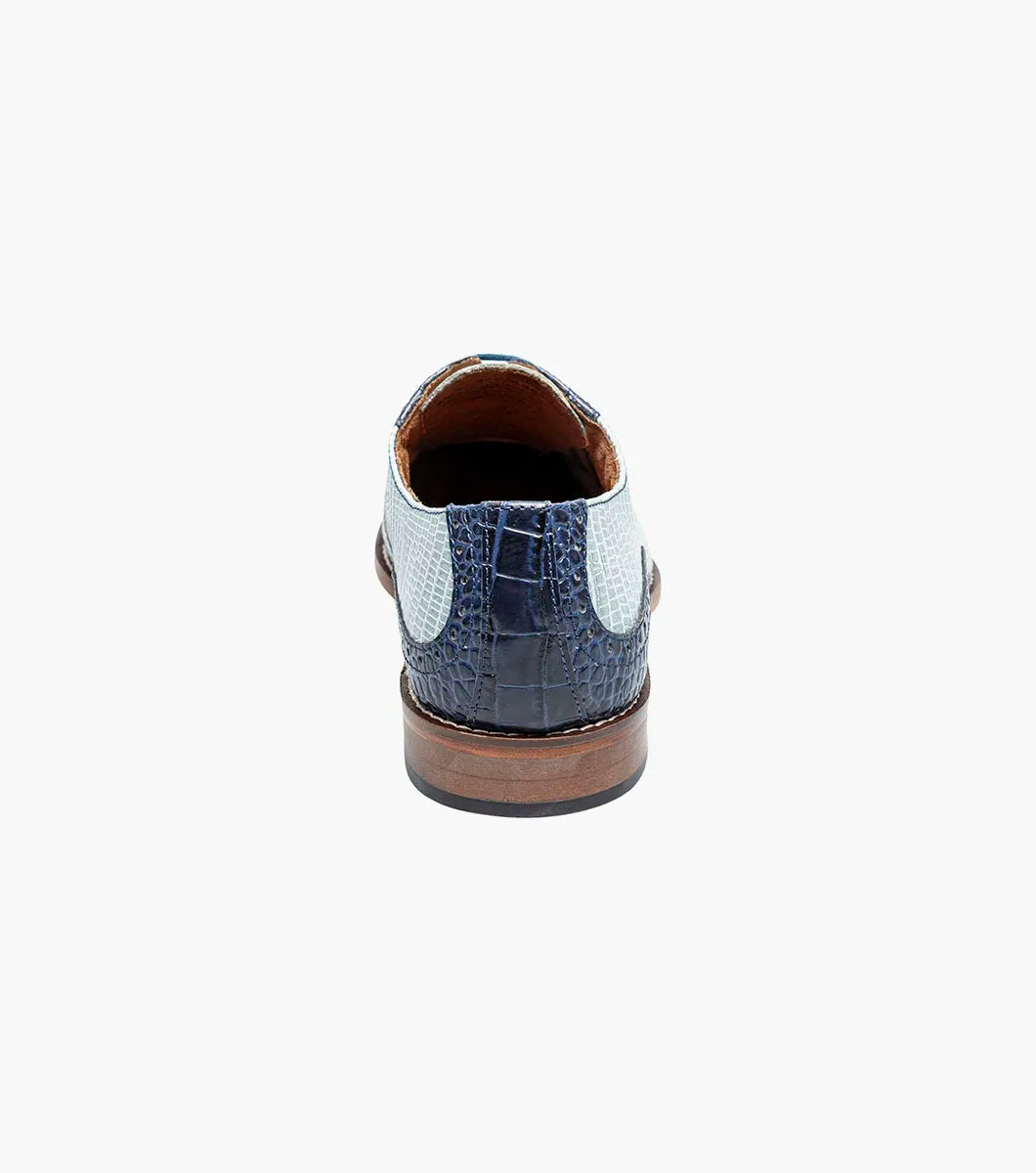 The Stacy Adams Tarango Modified Cap Toe Oxford in Dark Blue Multi features pointed toes, gray and blue crocodile print leather, and a low wooden heel—ideal for formal shoe enthusiasts.