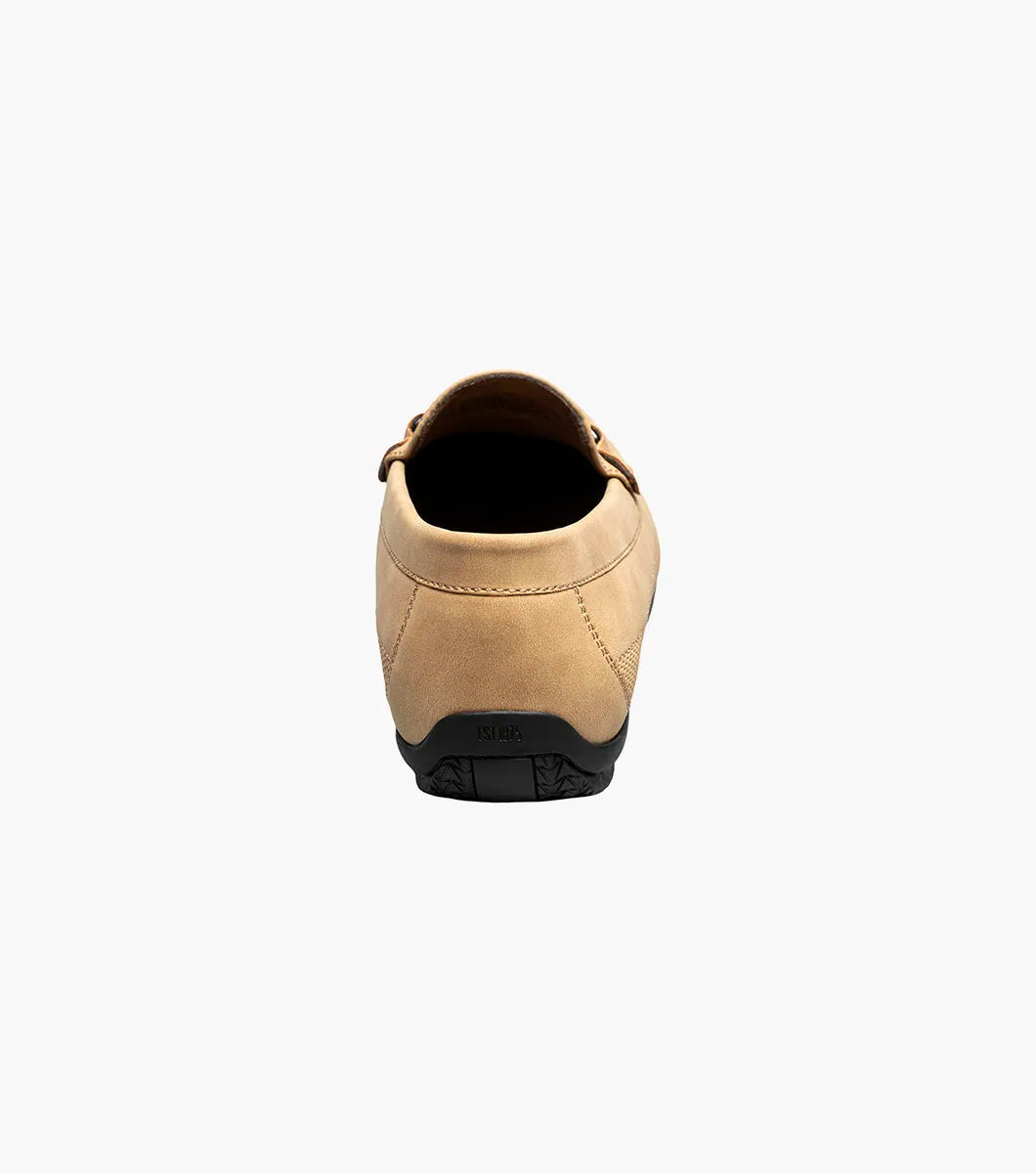 The Stacy Adams Colton Moc Toe Bit Slip On in khaki features a stitched moc toe, metal bit detail, black rubber sole, multicolored striped lining, and cushioned footbed for all-day comfort.