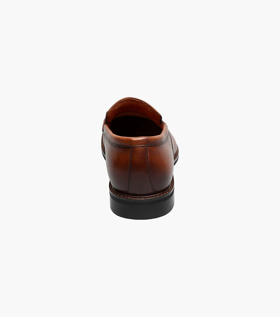The Stacy Adams Boyd Moc Toe Bit Slip On in Brandy features a brown leather upper, moc toe design, metal horsebit detail, low heel, cushioned footbed, and visible stitching. Model 25753-226 by STACY ADAMS shown on a white background.