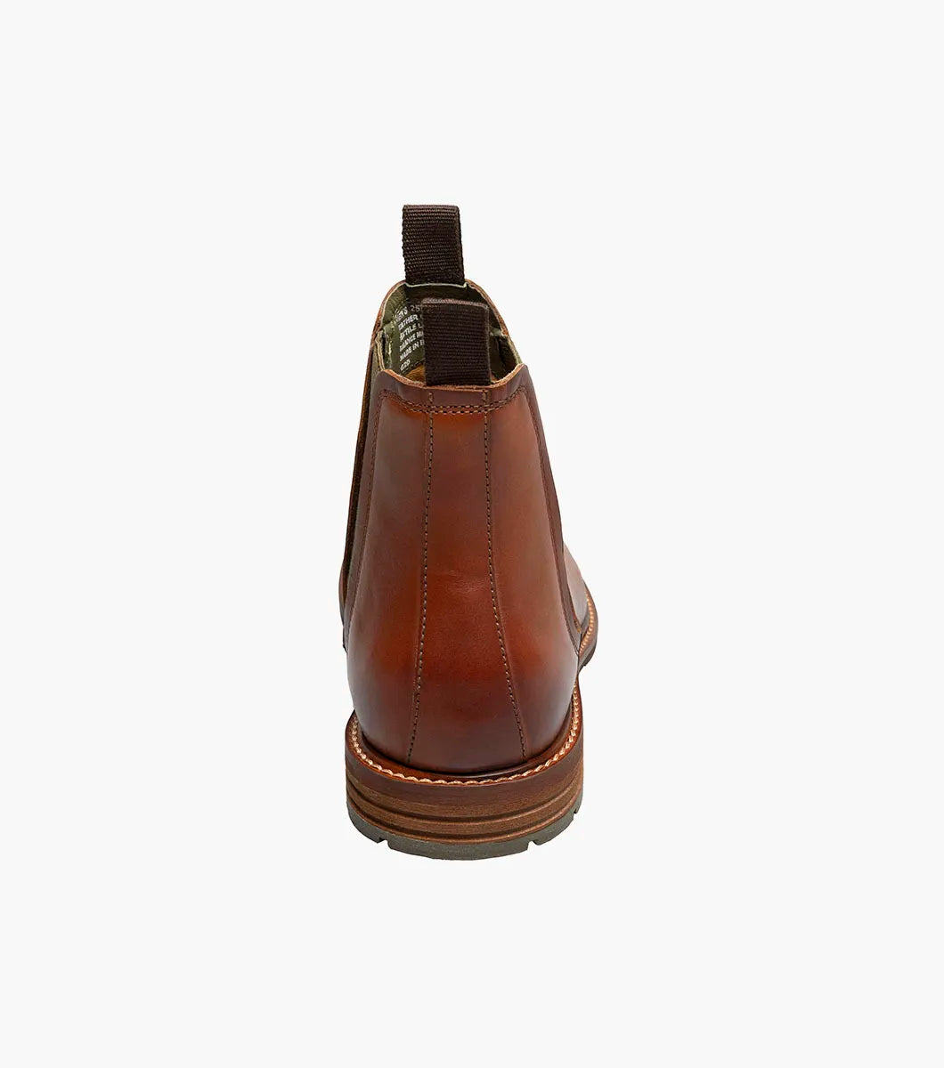 The Stacy Adams Isaacson Plain Toe Chelsea Boot in Cognac features elastic side panels, pull tabs, a low stacked heel, and a supportive leather upper—all displayed on a white background.