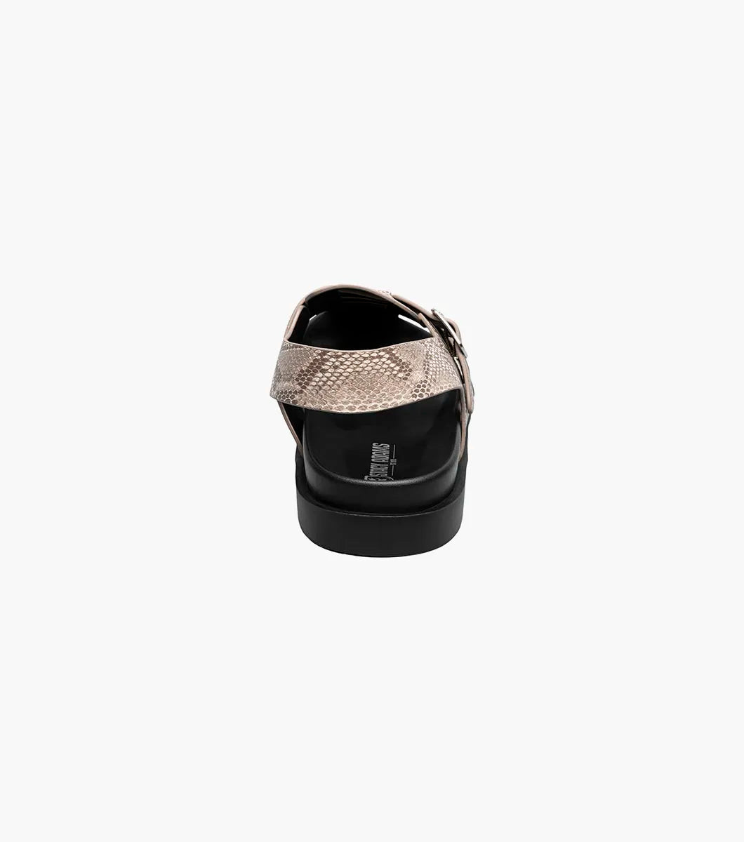 The Stacy Adams Montego Slingback Buckle Sandal (Sand, 25659-269) features a tan snakeskin pattern, closed toe, cutout sides, adjustable buckle strap, black sole, and cushioned EVA midsole on a white background.