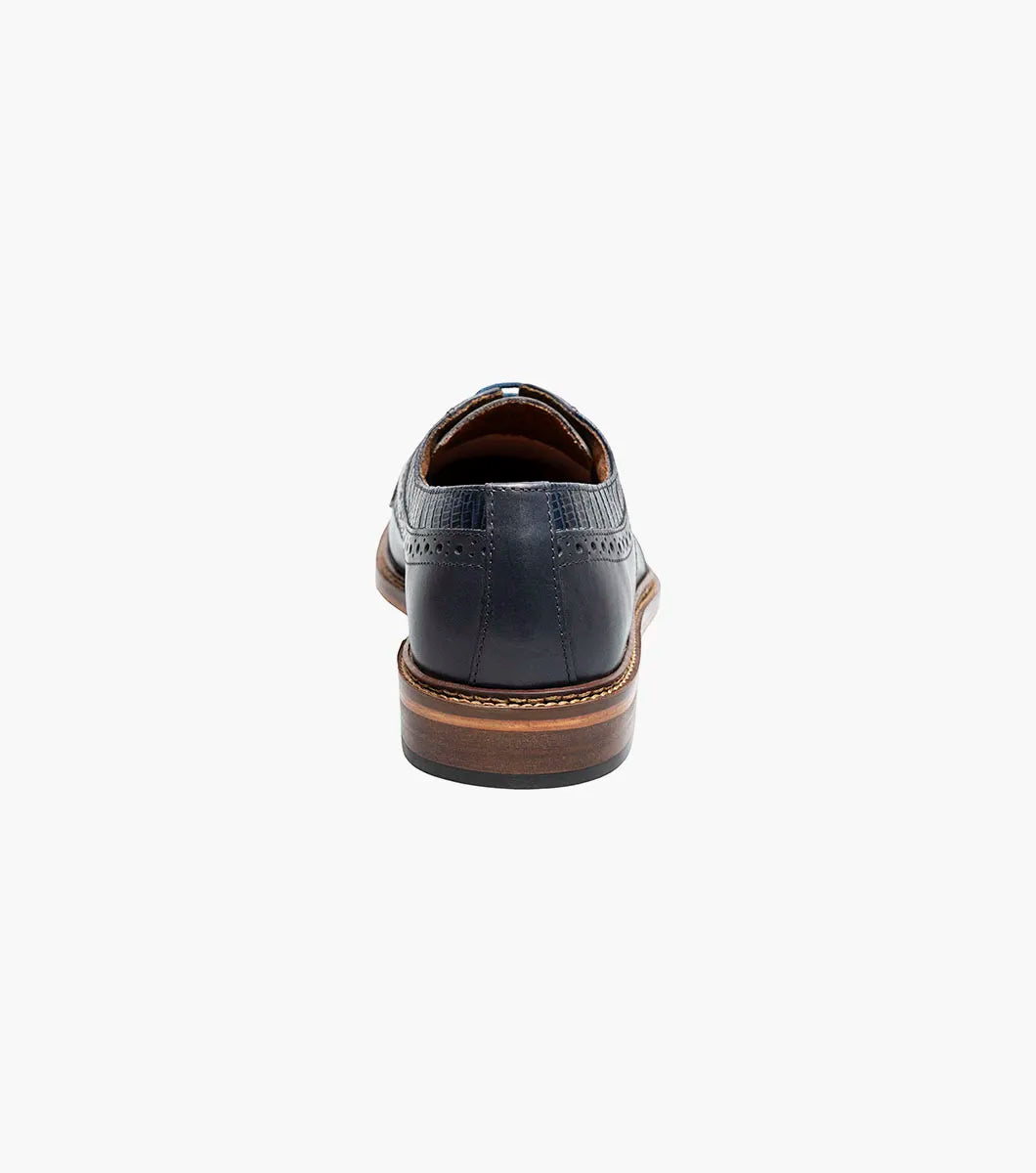 The STACY ADAMS Gambetta Modified Cap Toe Oxford (Navy, 25780-410) is a navy blue leather dress shoe featuring a textured pattern, brown sole, RedZone footbed, and lace-up closure, displayed on a white background.