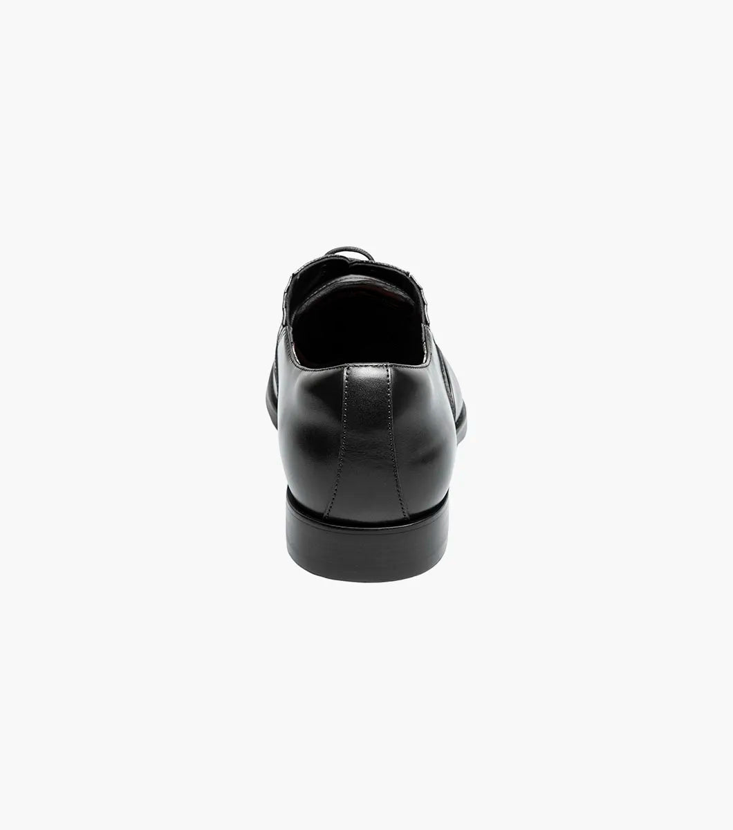 The STACY ADAMS Lucas Cap Toe Oxford (25766-001) is a black leather men's dress shoe with textured side panels, black laces, and a supportive RedZone footbed, shown on a plain white background.
