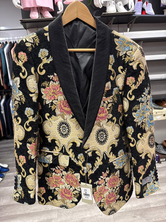 JACKET 13 CLEARANCE by EJ SAMUEL: Black blazer with a floral brocade pattern in gold, blue, red, and tan tones, featuring a shawl collar and displayed on a wooden hanger in a clothing store. Please note: this item is final sale with no returns or exchanges.