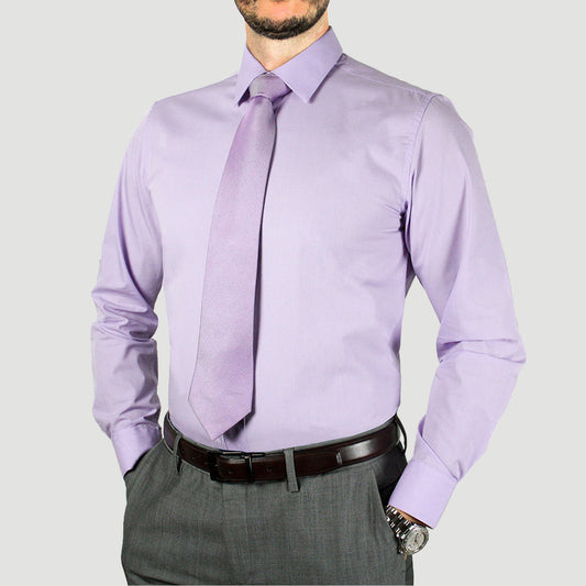 A person wearing an Arturo Modern Fit Long Sleeve Lilac Dress Shirt (4X to 6X) paired with a matching tie and gray pants, hands in pockets, with a watch on the left wrist.
