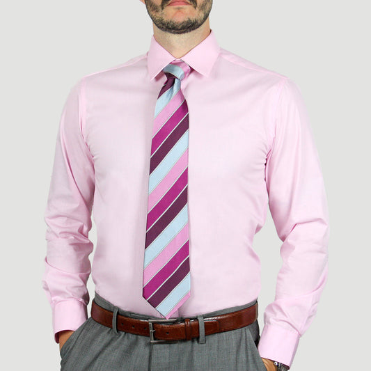 A person wearing the Arturo Modern Fit Long Sleeve Pink Dress Shirt, along with a striped tie in shades of pink and blue, and gray trousers with a hint of spandex that pair perfectly with a brown belt.