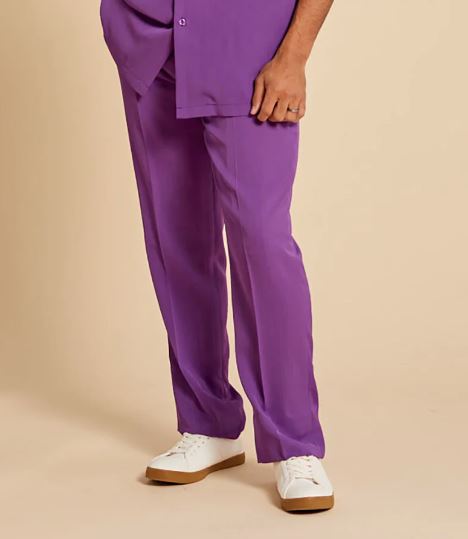 A person wears the Inserch 2pc Set (Shirts and Pants) in Plum, by Inserch—featuring a regular fit, short-sleeve button-up shirt and matching pants—standing with one hand in their pocket against a beige background.