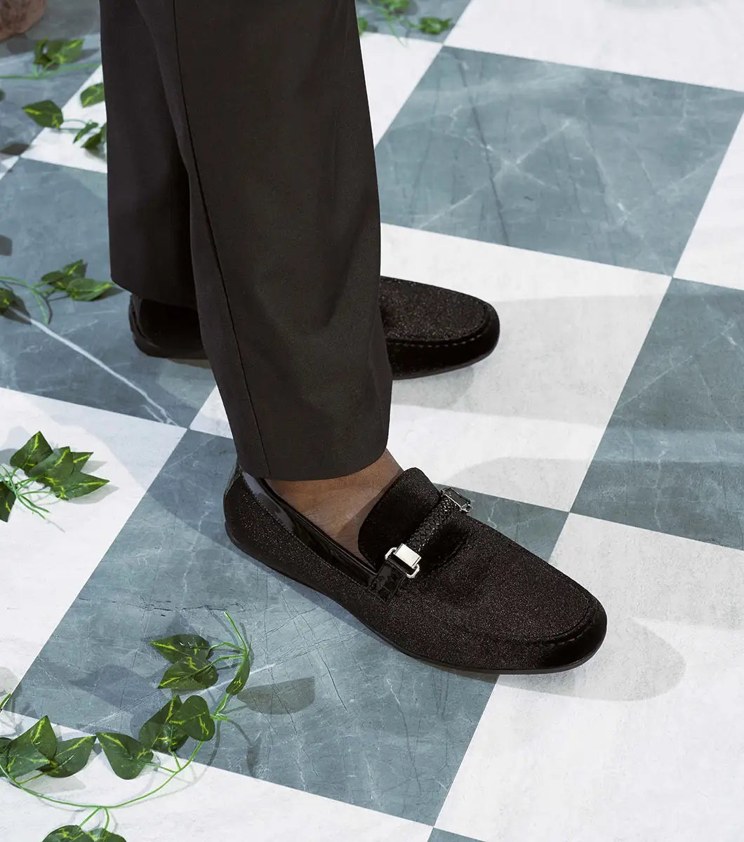 The Stacy Adams Sheridan Moc Toe Bit Slip On (black, 25761-001) is a sleek black suede dress shoe with braided detail and metal accent, low heel, and satin-lined interior for comfort.