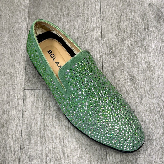 The Exclusive Formal Dress Shoe Green SNYDER from UNIQUE DESIGN MENSWEAR is a sparkling green slip-on shoe with a flat sole, made from premium suede leather and placed on a gray wooden floor.