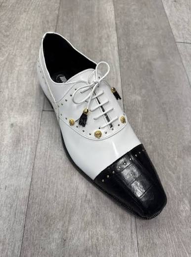 Mauri 4901 Vegas Black White (SIZE 11 ONLY) (FINAL SALE) by Mauri – a single white dress shoe featuring gold studs, black tassels, and a glossy black square toe, displayed on a wooden floor. Please note: FINAL SALE—no exchanges or returns accepted.