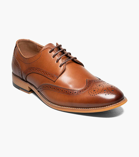 The Stacy Adams David Wingtip Oxford in Cognac (20185-221) is a brown leather dress shoe featuring decorative perforations, laces, a low wooden heel, and a plush memory foam insole, shown on a white background.
