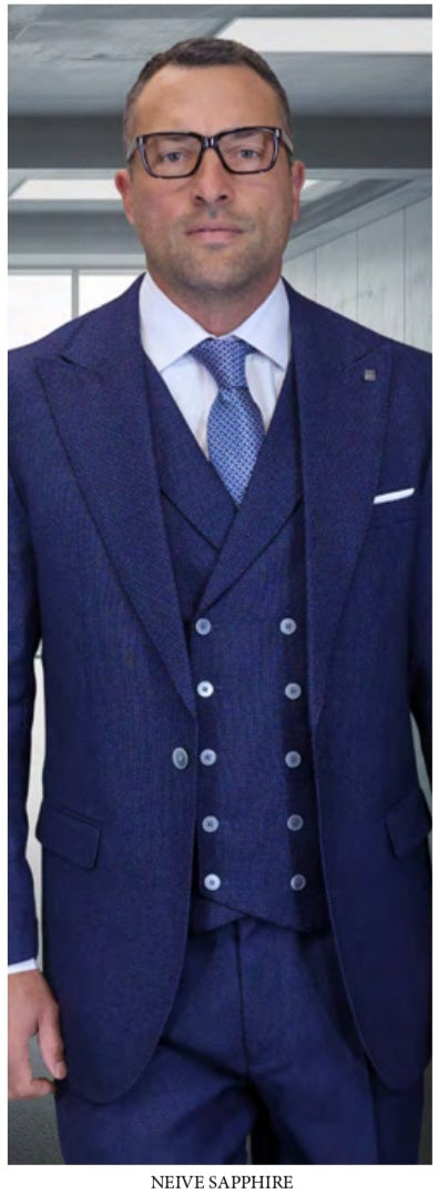 A man in glasses wears the STATEMENT CLOTHING | NEIVE-SAPPHIRE by Statement Clothing—a tailored sapphire blue three-piece suit with a double-breasted vest and tie, standing indoors.