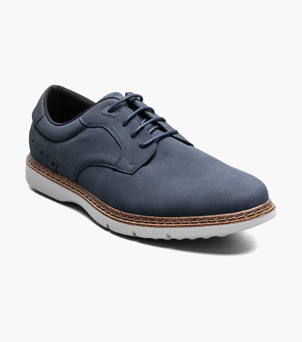 The STACY ADAMS Skyler Plain Toe Oxford in navy (style 21532-410) is a casual lace-up shoe crafted from man-made suede, featuring a white sole, brown stitching along the edge, subtle side perforation details, and a cushioned insole for enhanced comfort.
