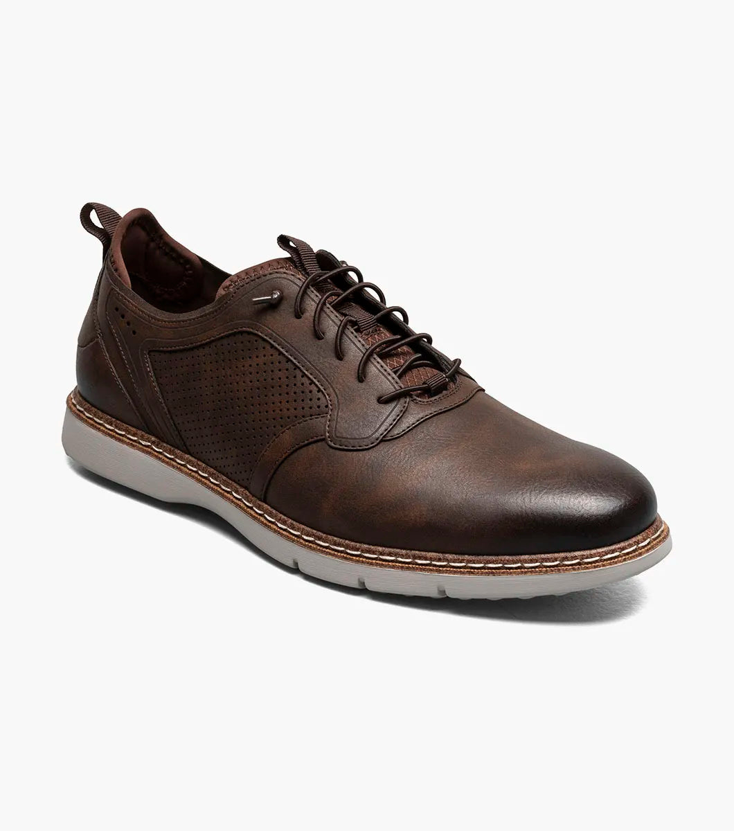 The STACY ADAMS Score Plain Toe Elastic Lace Up in Brown (style 21538-215) is a business-casual leather shoe featuring perforated side panels, a white sole, elastic lace-up front, and detailed stitching with a supportive RedZone footbed—displayed against a plain white background.