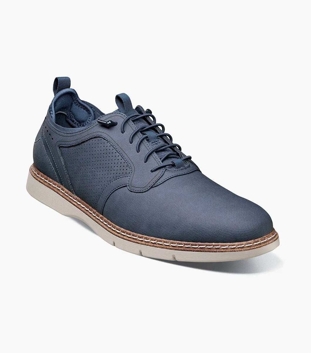 The STACY ADAMS Score Plain Toe Elastic Lace Up in navy (style 21538-410) is a blue dress shoe with elastic laces, featuring a perforated side panel, tan stitching, and a light-colored sole on a white background. It includes anatomical arch support for enhanced comfort.