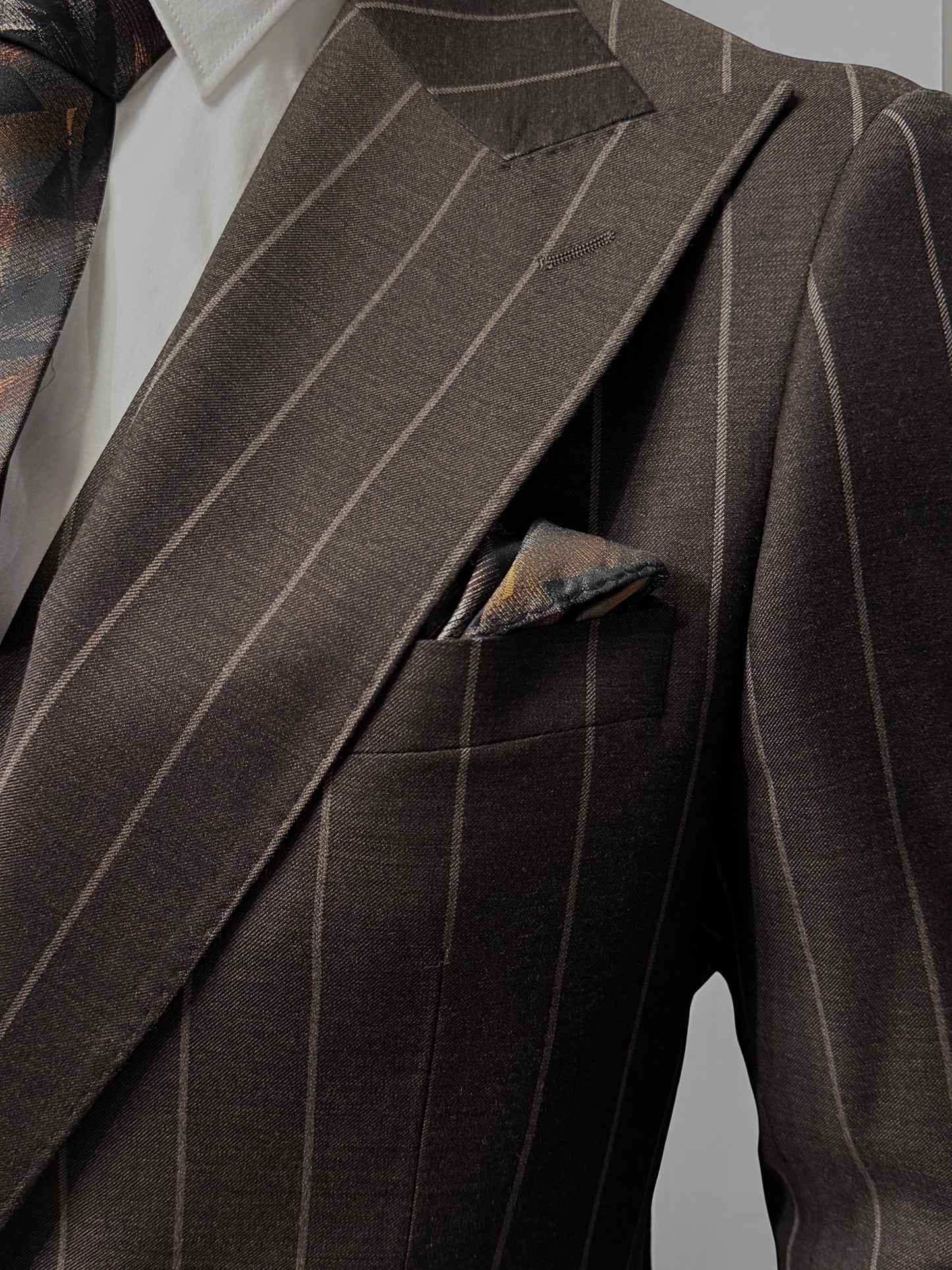 A mannequin displays the Tiglio Rosso Orvietto Brown Pinstripe TL8101 suit with a white shirt and patterned tie, highlighting the classic style of Tiglio Rosso against a simple light background.