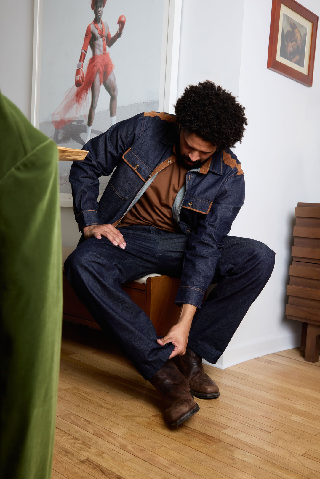 A man stands against a beige background wearing the Inserch Denim Shirt w/ Suede Trim 2pc Set in indigo by Inserch, paired with an orange sweater and dark brown shoes.