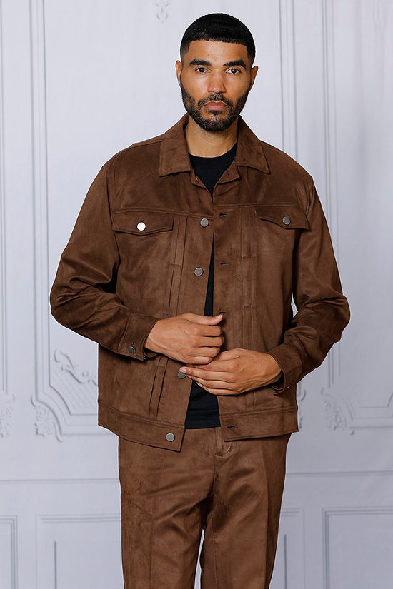A man wearing the INSOMNIA ROMEO 2PC Brown Vegan Suede Leisure Suit by Insomnia stands against a white wall with decorative molding, looking to the side.